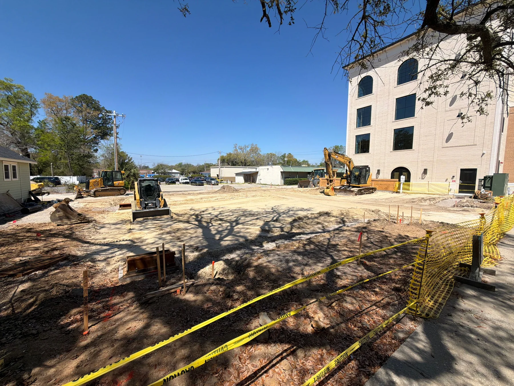Commercial site construction with excavation equipment and grading beside an existing building