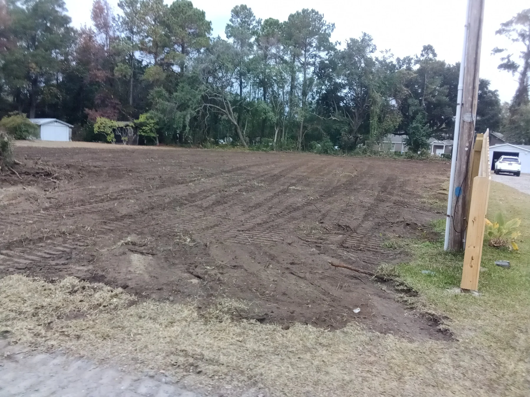 A cleared lot with worked soil and equipment-track marks.
