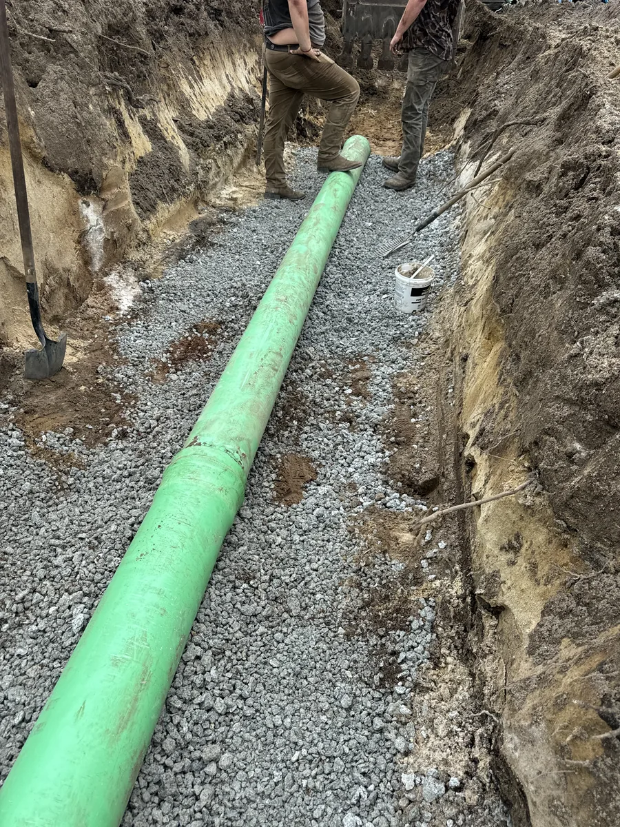 Green sewer pipe installed on stone bedding